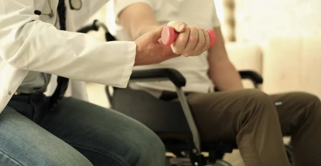 Physiotherapeut trainiert Patienten mit Hanteln.