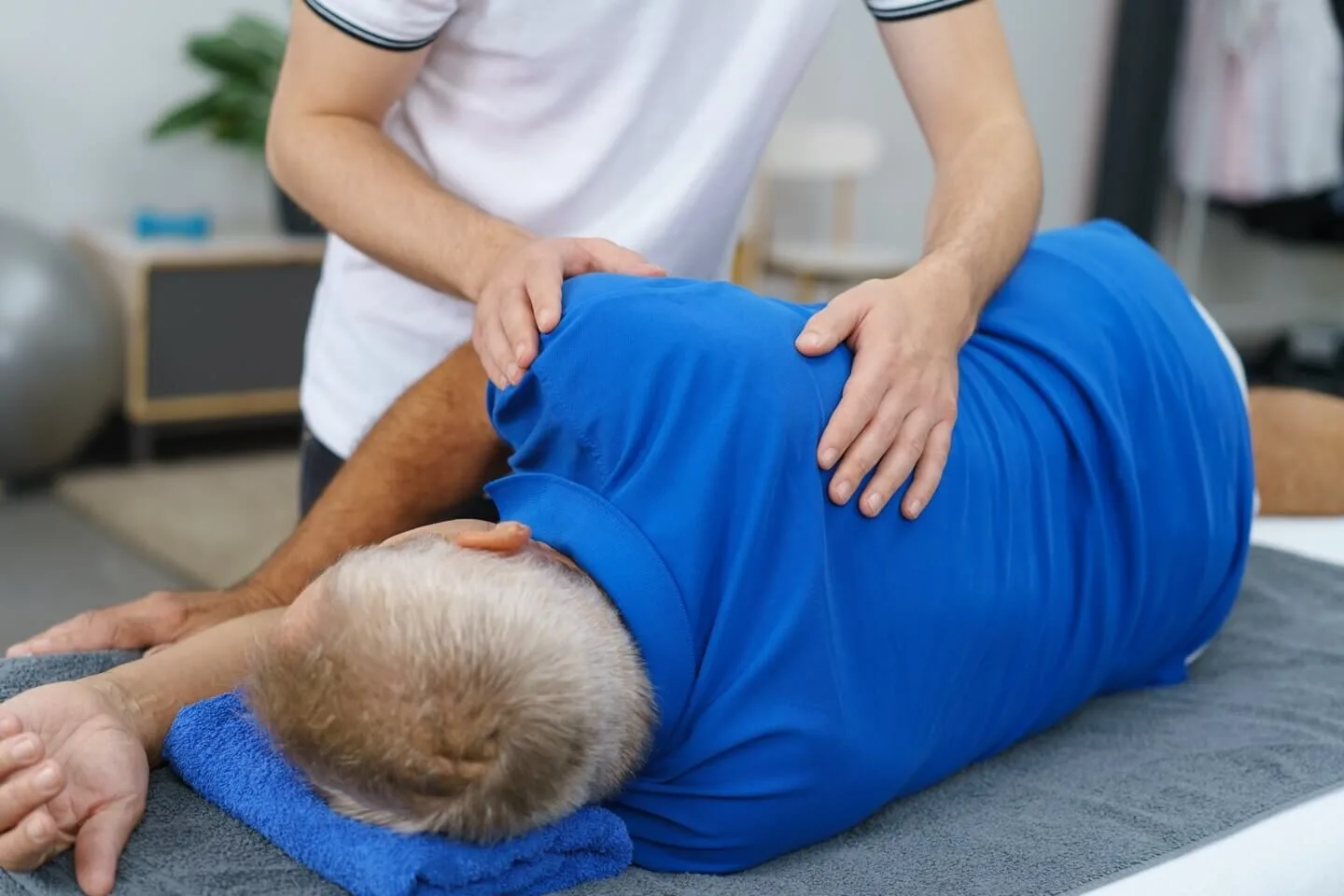 Header Bild - Patient auf Liege mit Behandlung durch Therapeut am Rücken