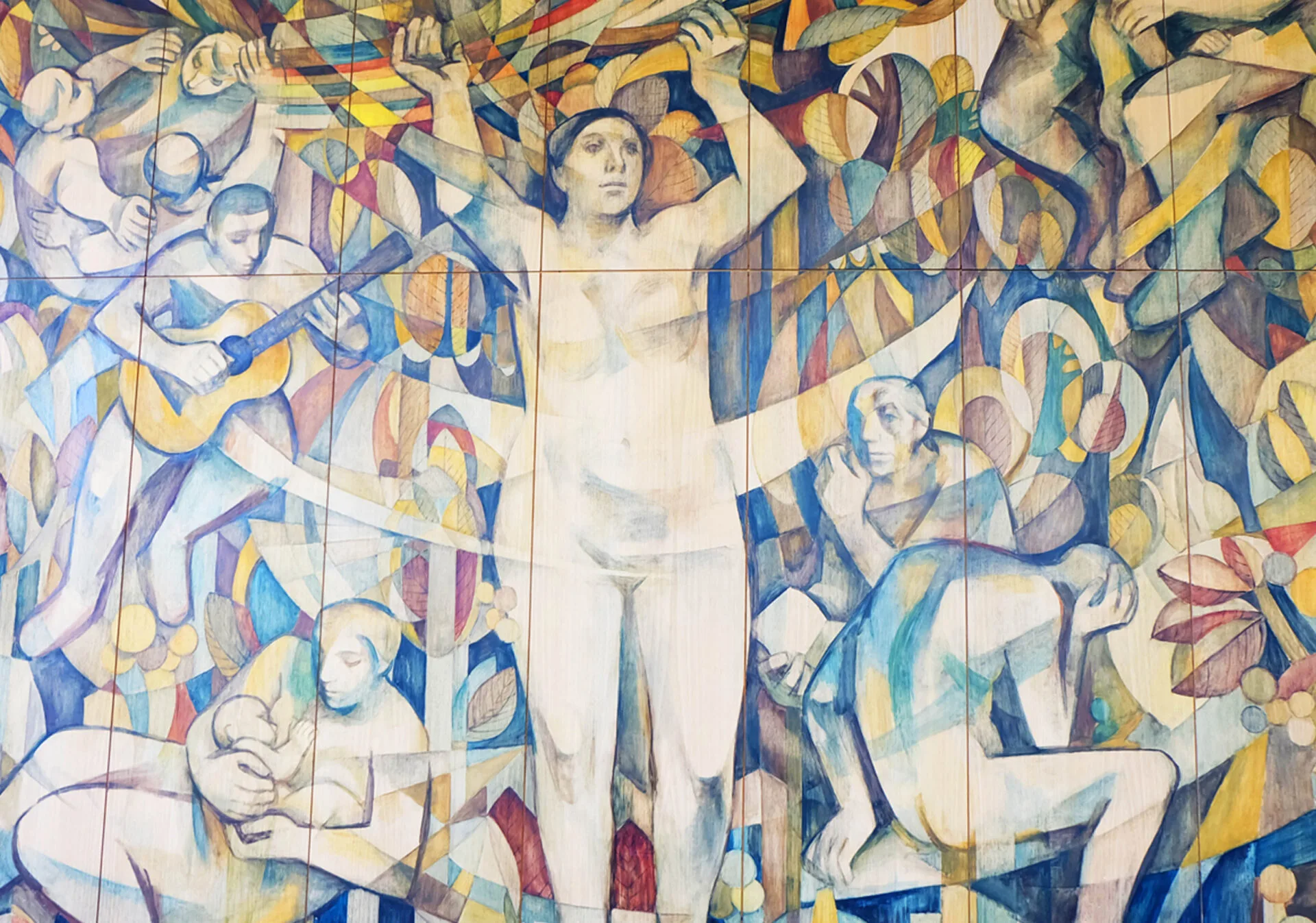 Das Bild ist ein Wandgemälde oder eine bemalte Wand, die eine Vielzahl von menschlichen Figuren in verschiedenen Posen darstellt. Die Stilelemente sind abstrakt und verwenden eine gedämpfte Farbpalette mit blauen, gelben und violetten Tönen. Eine zentrale Figur ist eine nackte Frau mit erhobenen Armen, die im Mittelpunkt steht. Weitere Figuren umfassen einen Gitarre spielenden Mann, eine stillende Mutter und eine Person, die in Gedanken versunken zu sein scheint. Die Komposition ist dicht und dynamisch, wobei sich die Figuren überlappen und ineinander verschmelzen. Das gesamte Bild strahlt eine Atmosphäre von Gemeinschaft, Kreativität und Reflexion aus.